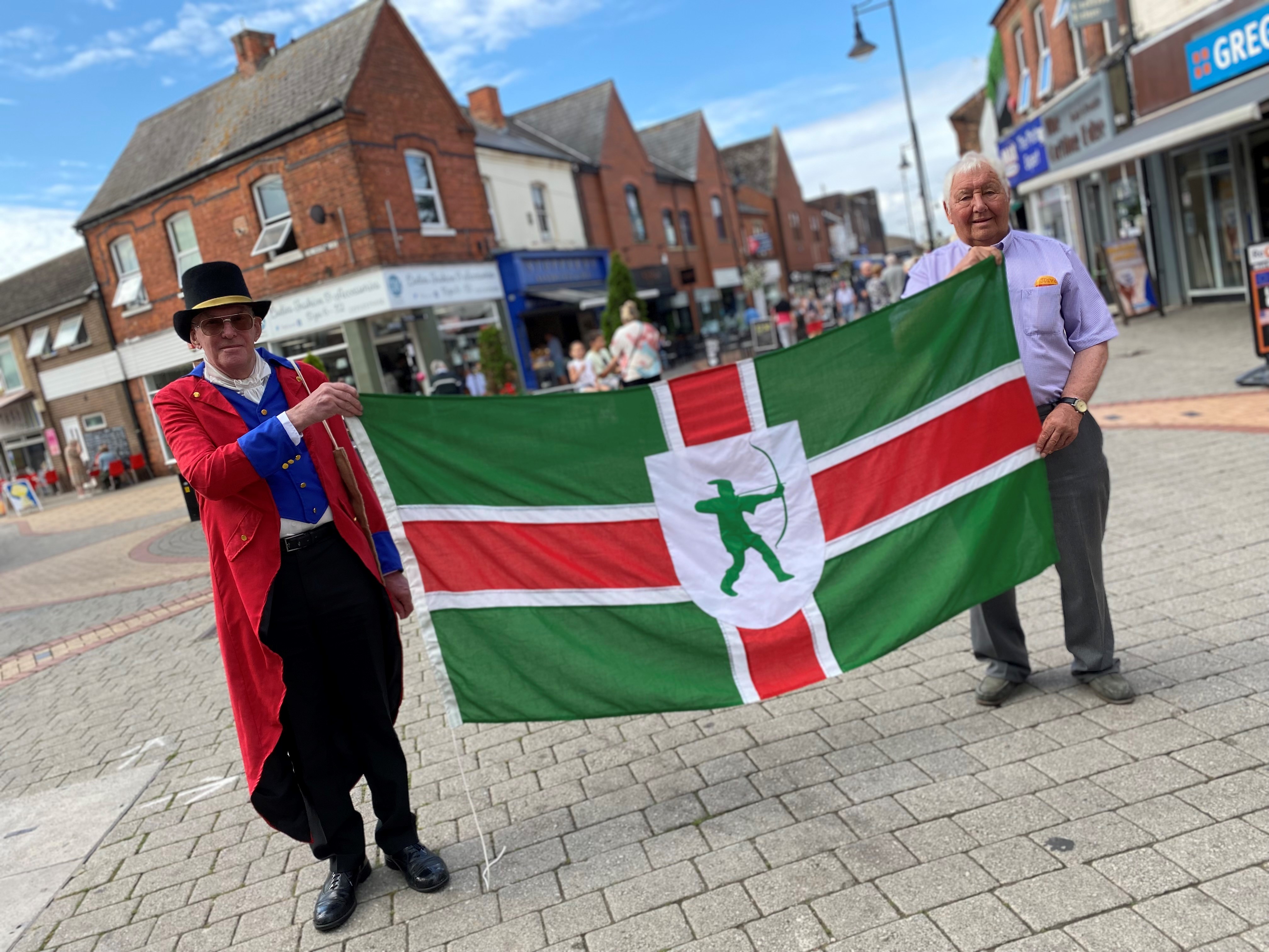 Mayor and local historian holding the Notts flag in Arnold Town Centre.